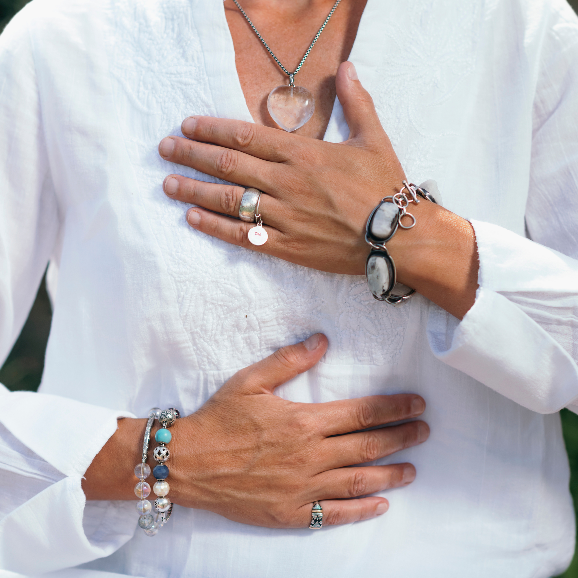 Photo of a woman's hands placed on her heart and stomach in a meditation pose.