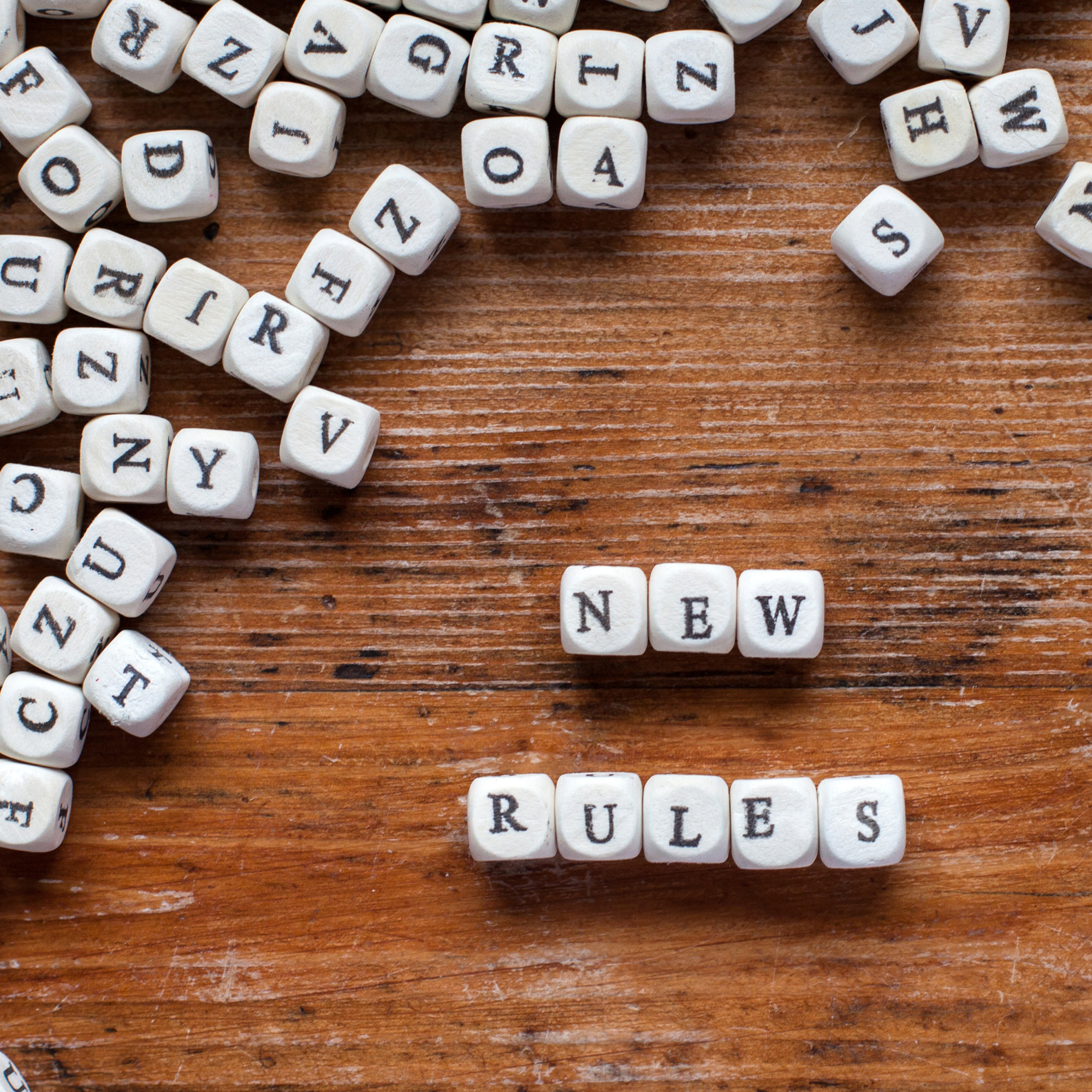 Photo of a wooden table with letter blocks that spell out "new rules/"