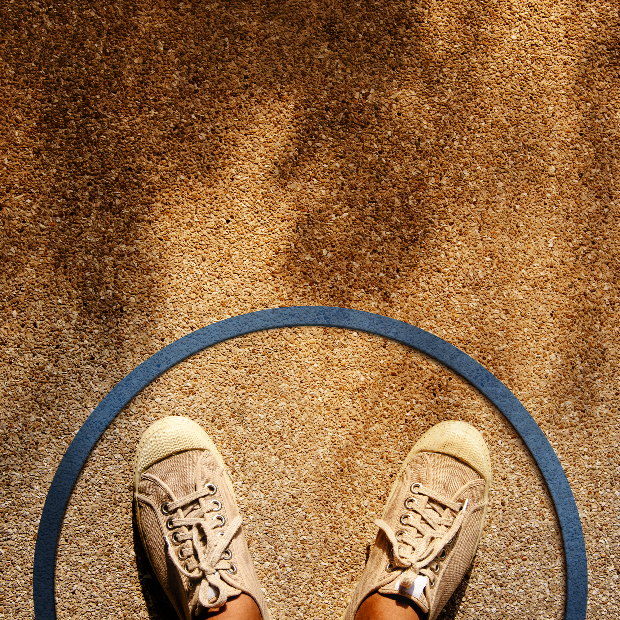 A photo looking down to the ground featuring a person's sneakers framed by a circular ring.