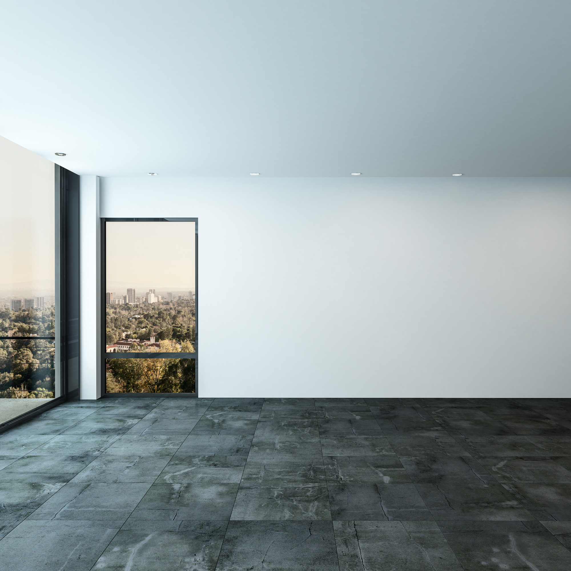 An modern empty room with floor to ceiling windows with a view of a park and city.