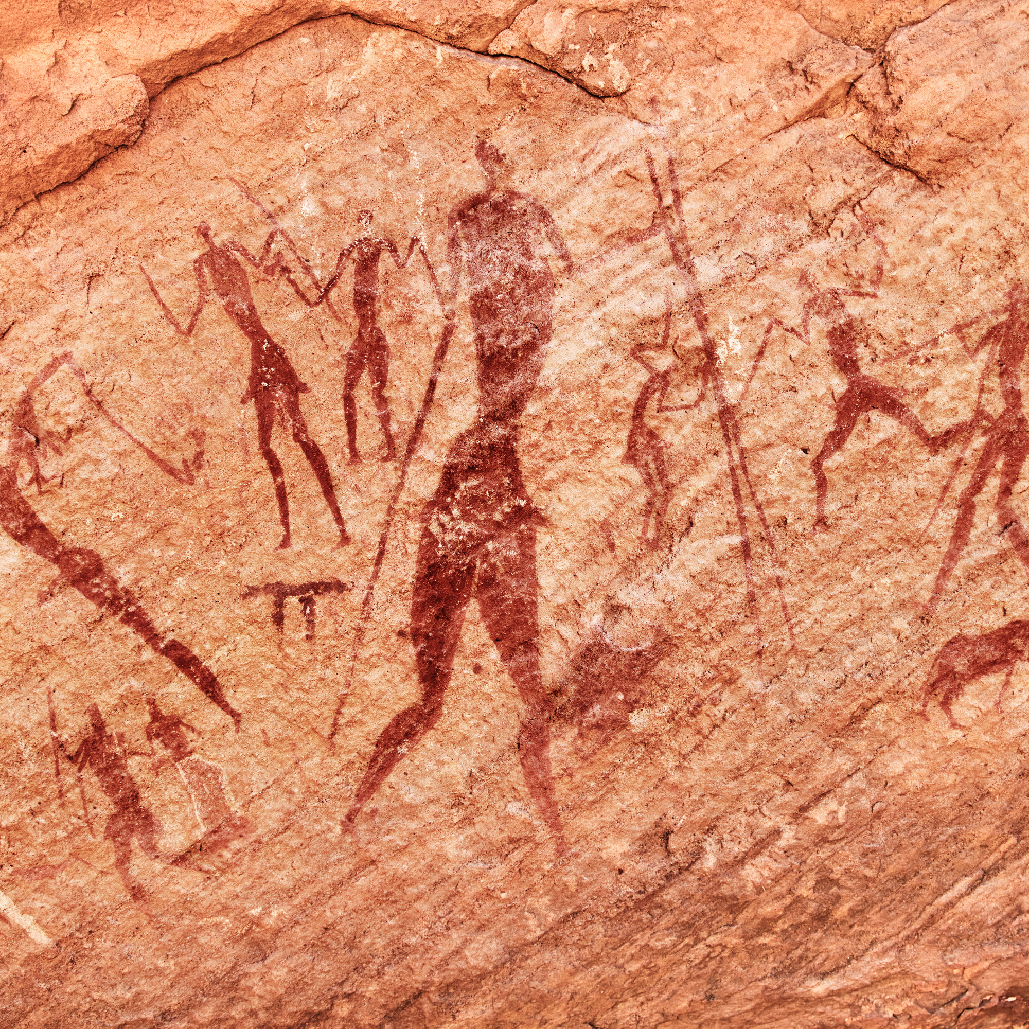 Photo of cave drawings depicting people holding tools.