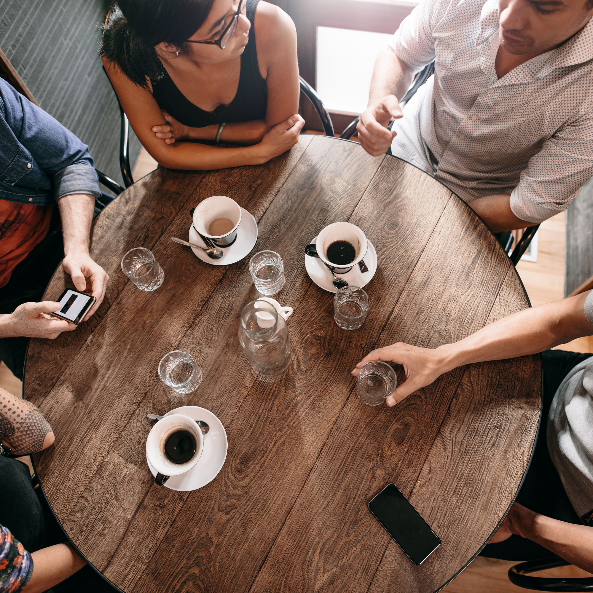 group of adults sitting and talking around a table at a coffee shop