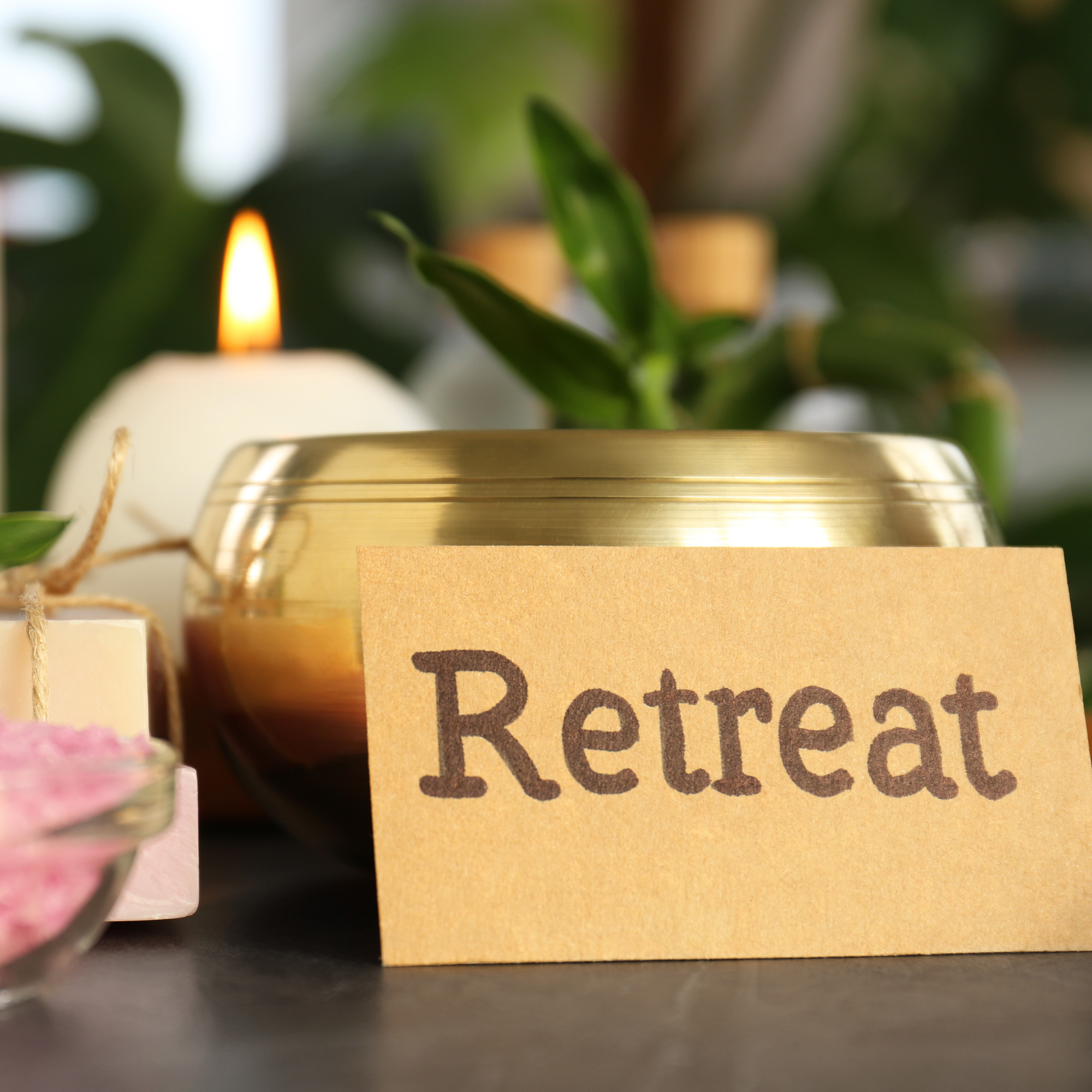 photo of candle, brass urn with plant and sign that reads "retreat"