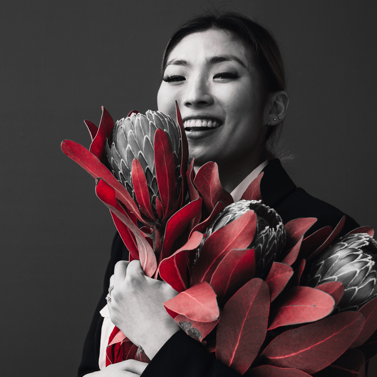 a smiling woman holding a bouquet of exotic cone-shapedflowers