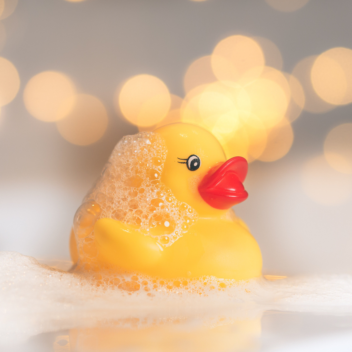 close up of a yellow rubber ducky toy in a bubble bath