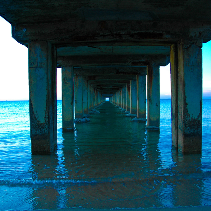 A photo looking out on the ocean as seen from the underside of a pier.
