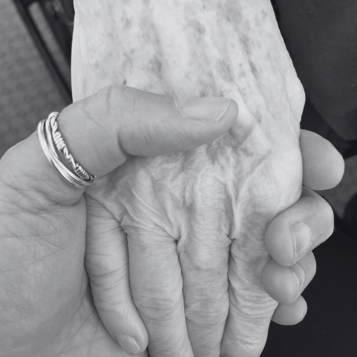 Closeup photo of a daughter (the author) holding her elderly mother's hand