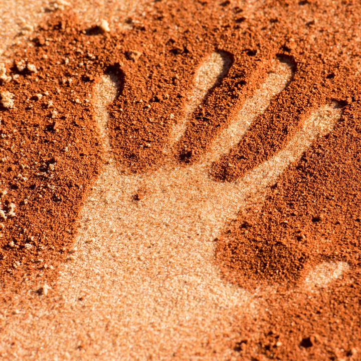 photo of a handprint in bronze-colored sand